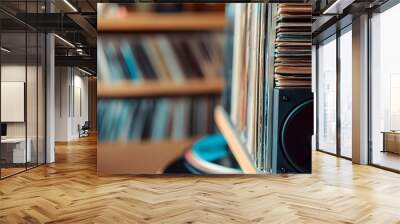 A close-up of vinyl records stacked beside a modern speaker blending the old-school vibe with contemporary sound equipment Wall mural