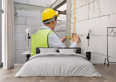 An Asian Engineering man wearing safety helmet checking construction site analyzing about project progress Wall mural