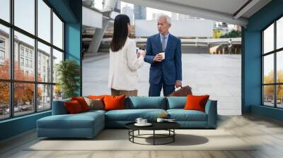 Asian senior mature middle aged businessman and young businesswoman having a discussion and coffee in modern city Wall mural