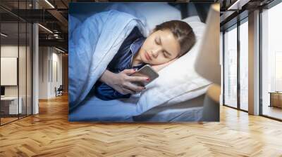 Beautiful woman is playing smart phone before sleep in bedroom Wall mural