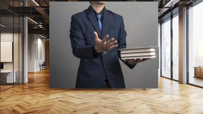 Close up of businessman in blue suit holding books on gray backg Wall mural