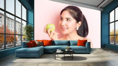 Healthy girl eating green apple on pink  background Wall mural