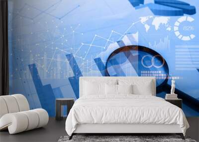 Magnifying glass and documents with analytics data lying on tabl Wall mural