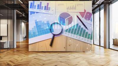 Magnifying glass and documents with analytics data lying on table,selective focus Wall mural