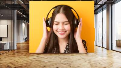 Music lover woman is enjoying with headset on yellow background Wall mural