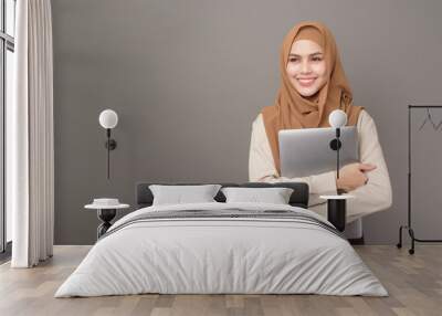 Portrait of beautiful woman with hijab is holding computer laptop on gray background Wall mural