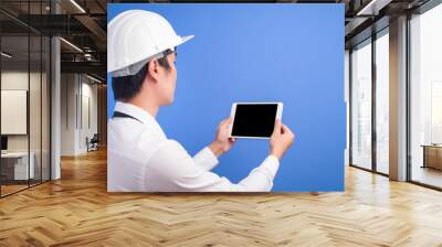 Portrait of confident male engineer wearing a white using tablet over blue  background studio Wall mural