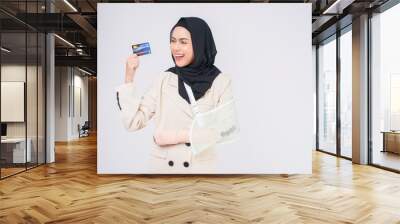 Portrait of young muslim woman with an injured arm in a sling over blue background in studio. Wall mural