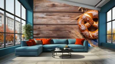 A charming Oktoberfest setting with a soft pretzel on a wooden table, decorated with hops, wheat, and blue-and-white Bavarian flags. The top right corner of the image includes a large blank space for Wall mural