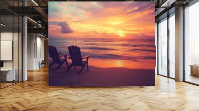 This stock photo features a tranquil beach at sunset with two empty beach chairs positioned near the water's edge. The end of summer is depicted with the sun setting on the horizon, casting long Wall mural