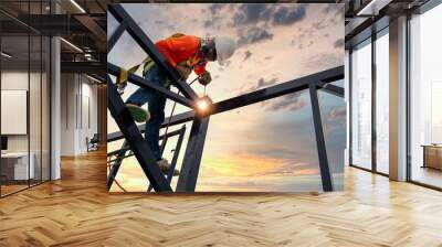 A welder is welding steel on a steel roof truss. Working at height equipment. Fall arrestor device for worker with hooks for safety body harness. Worker in construction site. Wall mural