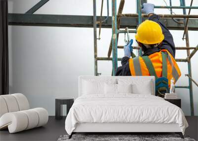 A worker working at height equipment. Fall arrestor device for worker with hooks for safety body harness on selective focus. Worker as in construction background. Wall mural