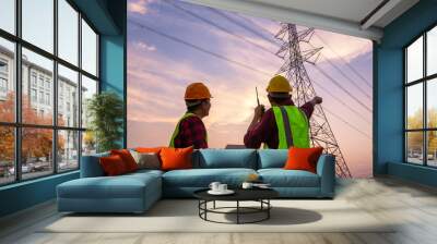 Asian Manager Engineering and worker in standard safety uniform working inspect the electricity high voltage pole. Wall mural