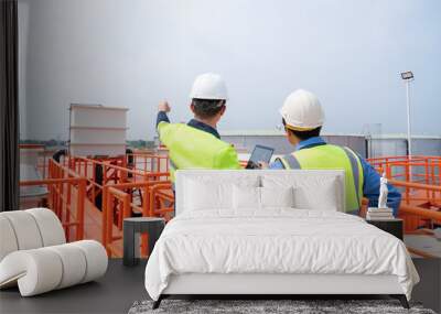 Back View of project leader holds a tablet and discusses product details with the chief engineer as they walk inspect the water supply process for an industrial plant. Wall mural