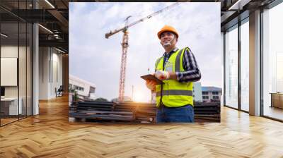 male construction engineer. Architect with a tablet computer at a construction site. Asian young man looking, building site place on background. Construction or building engineer concept Wall mural