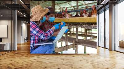 Two Asian farmers inspect and record the quality data of the chicken eggs using a laptop in eggs chicken farm. Wall mural