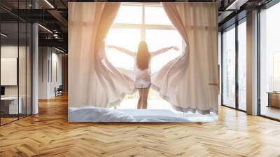 Young asian woman stand open white curtains at the window, the morning after waking up in the bedroom of her home. Woman wake up with a fresh and open the curtains on the windows. Wall mural