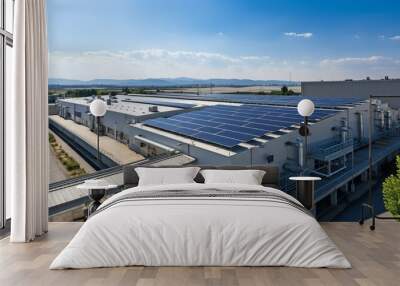 A manufacturing building's roof is covered in numerous solar panels.. Wall mural