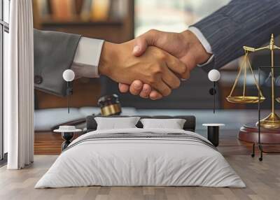 Close-up shot of a male lawyer negotiating and shaking hands with a guy client while seated at a desk in the office. Wall mural