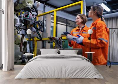 Girl engineer commissioning operating programming and looking at robot machine in the factory Wall mural