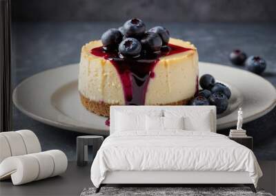 Round molded single serve piece cheesecake cake slice with blueberry sauce and blueberries on top on a white plate with a simple background Wall mural