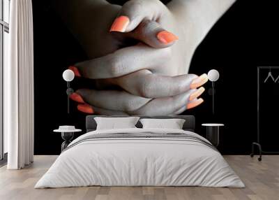 Selective focus of intertwined female hands with orange false nails, on black background. nail manicure Wall mural