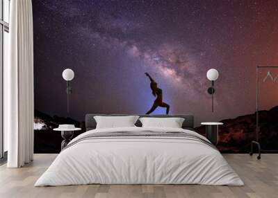 Landscape with Milky way galaxy. Night sky with stars and silhouette woman practicing yoga on the mountain. Wall mural