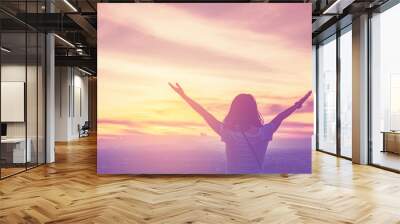 Copy space of woman rise hand up on top of mountain and sunset sky abstract background. Wall mural