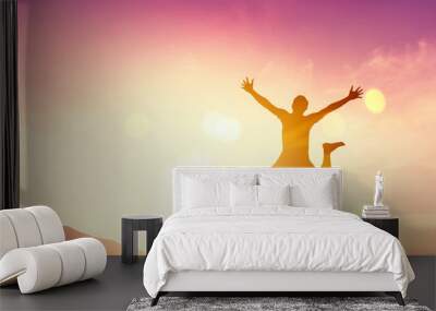 Happy man jumping at top of mountain with sunset sky abstract background. Wall mural