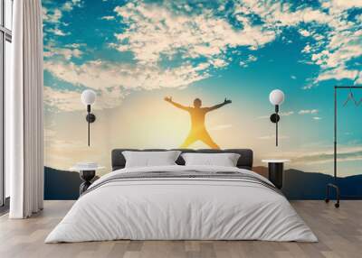 Happy man jumping at top of mountain with sunset sky abstract background. Wall mural