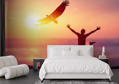 Happy man jumping at tropical beach with eagle bird flying on sunset sky abstract background. Wall mural