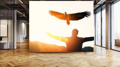 Man raise hand up on top of mountain and sunset sky with eagle bird fly abstract background. Wall mural