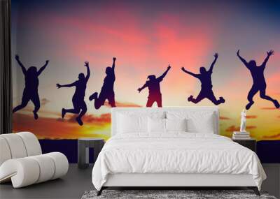 Silhouette happy friends jump on sunset sky at top of mountain abstract background. Wall mural