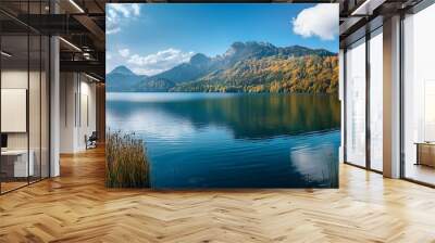 Tranquil lake surrounded by vibrant autumn foliage and mountains under a clear blue sky. Wall mural