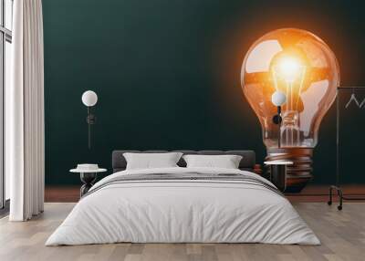 A lit light bulb resting on stacked coins, symbolizing innovation, energy efficiency, and financial investment against a green background. Wall mural