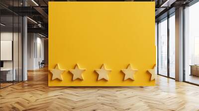 Five wooden stars arranged in a row on a vibrant yellow background, representing ratings and reviews in a minimalist flat lay style. Wall mural