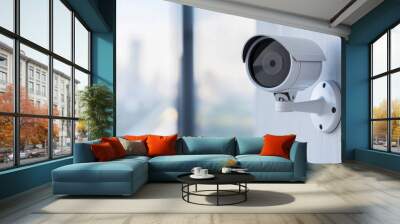 Modern surveillance camera mounted on a wall with urban city background, emphasizing security and safety in professional and residential areas. Wall mural