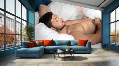 Shirtless sexy hunky man with beard lies naked in bed Wall mural