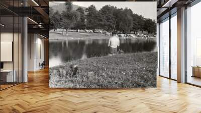 Old photo with a young fisherman catching fish in the background a herd of cows with a shepherd is crossing the river Wall mural