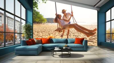 Romantic couple in love playing together on rope swing at summer beach for fun and happy smile. young man and woman on holidays or honeymoon Wall mural