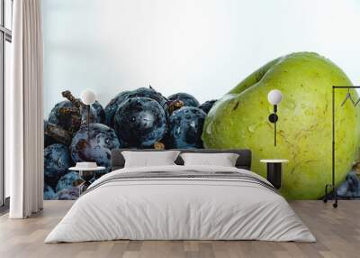 Bright purple grapes and green apples in a wooden basket on a white background. Wall mural