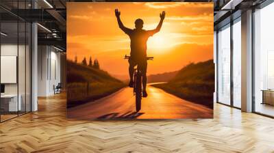 a man riding a bicycle on a road at sunset Wall mural