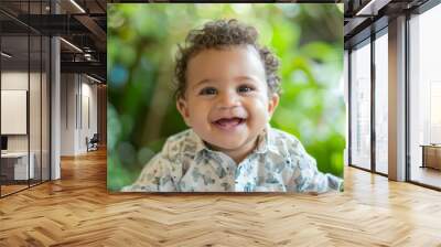 A baby with a smile on his face is wearing a white shirt with a pattern of anima Wall mural