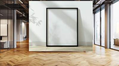 A black framed white picture is sitting on a wooden floor Wall mural