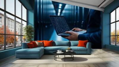 A man is holding a laptop in a dark room with a blue background Wall mural