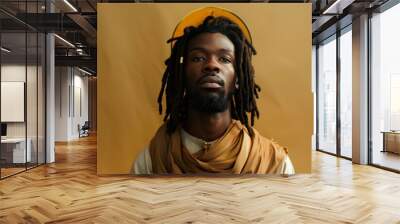 A man with dreadlocks and a yellow hat is standing in front of a yellow background Wall mural