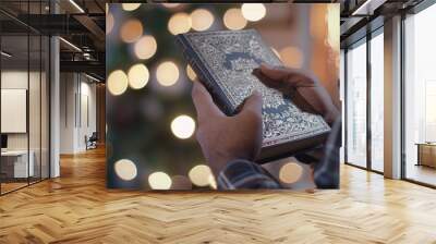 A person is holding a book with a gold embossed lettering on the cover, prayer concept Wall mural