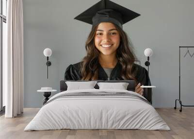 A woman in a black graduation gown is smiling and posing for a picture Wall mural