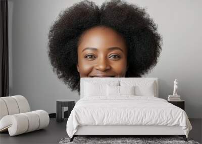 A woman with curly hair is smiling and posing for a picture Wall mural