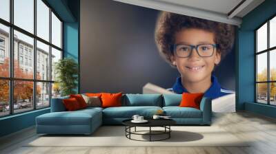 A young boy with glasses is reading a book Wall mural